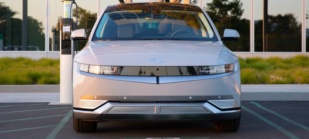 Front close up view of a 2024 Hyundai IONIQ 5 parked and plugged into a charger.