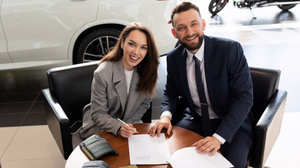 Person buying a car at a dealership with the sales person sitting next to them