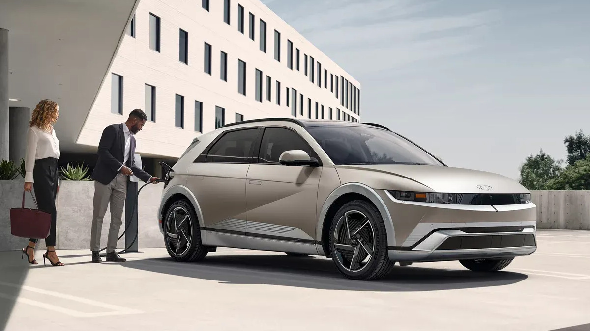 Side view of a 2026 Hyundai IONIQ 5 with a person plugging it in the charger.
